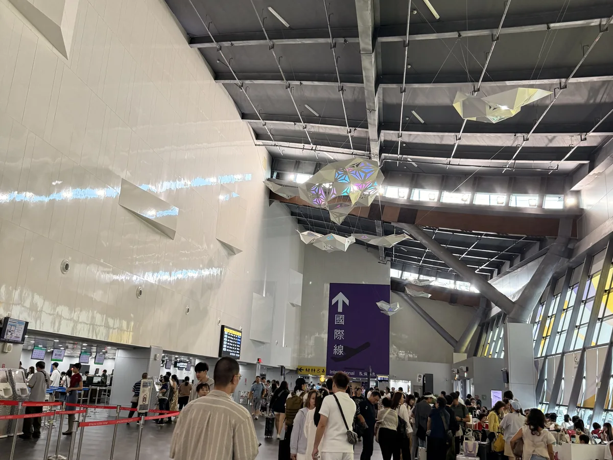臺中國際機場出境大廳的報到櫃檯與行李託運區，排隊的旅客與行李推車