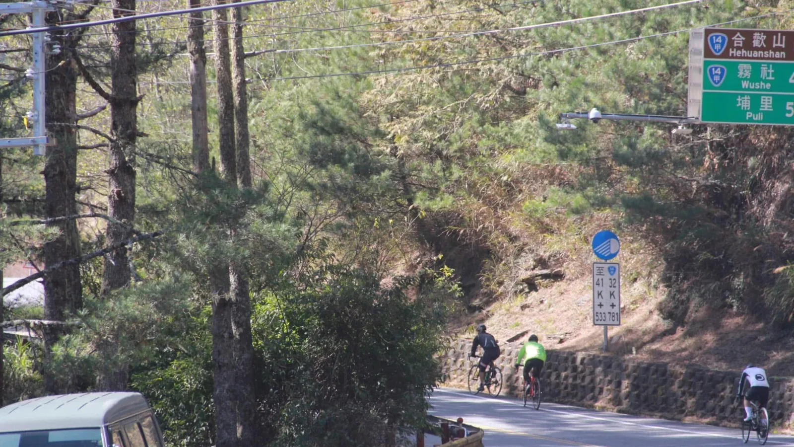 三位公路車騎士爬行台14甲線，路旁指標寫著合歡山、霧社與埔里