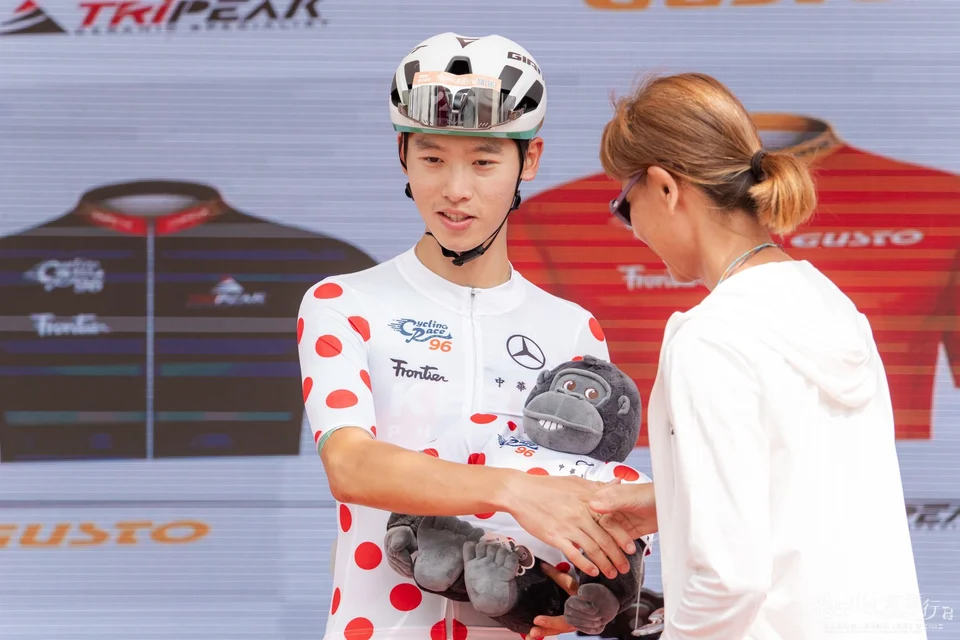 穿紅色圓點衫的選手在頒獎台上與頒獎人握手